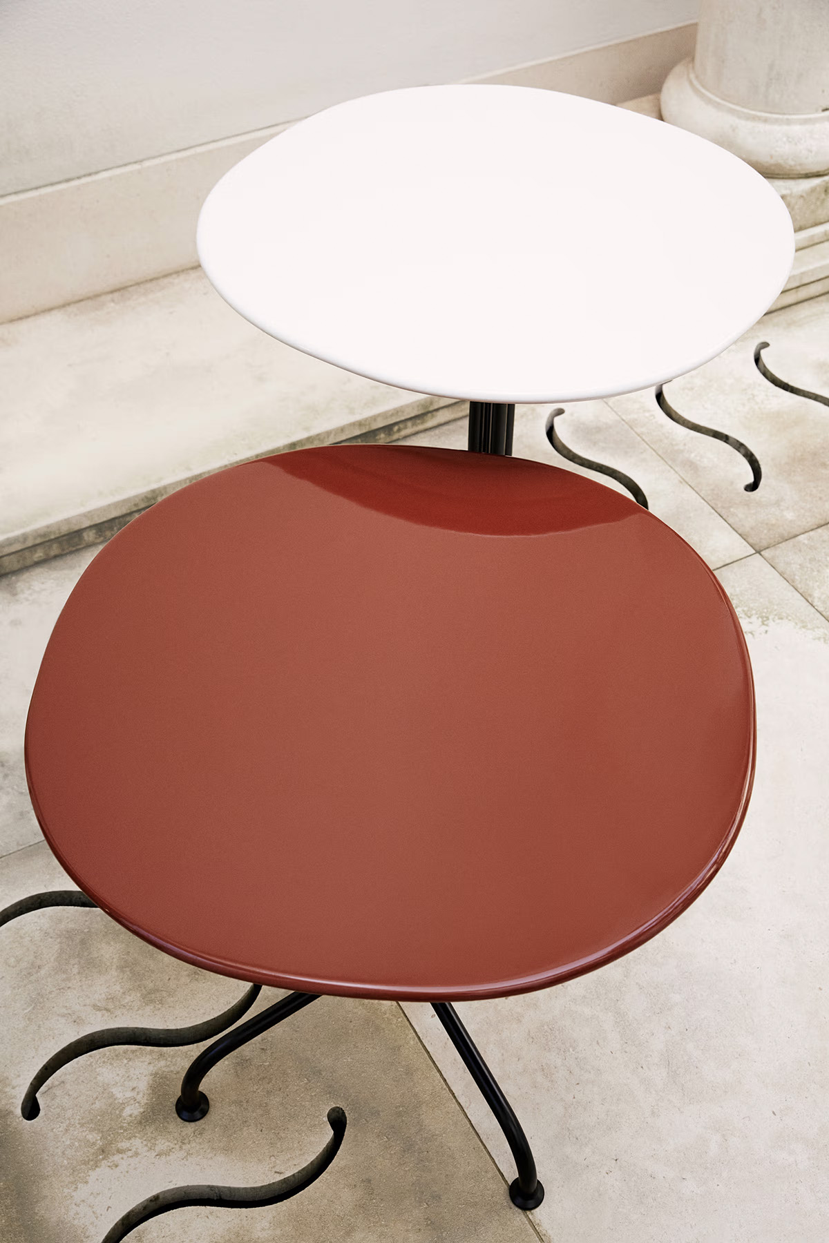 Gubi's Carmel Bistro Tables by OEO Studio blend café culture with poolside elegance. Featuring glazed Italian stoneware tops in Red Rock and Clam White with black stainless steel legs, these versatile pieces bring sophisticated charm to both indoor and outdoor dining experiences.