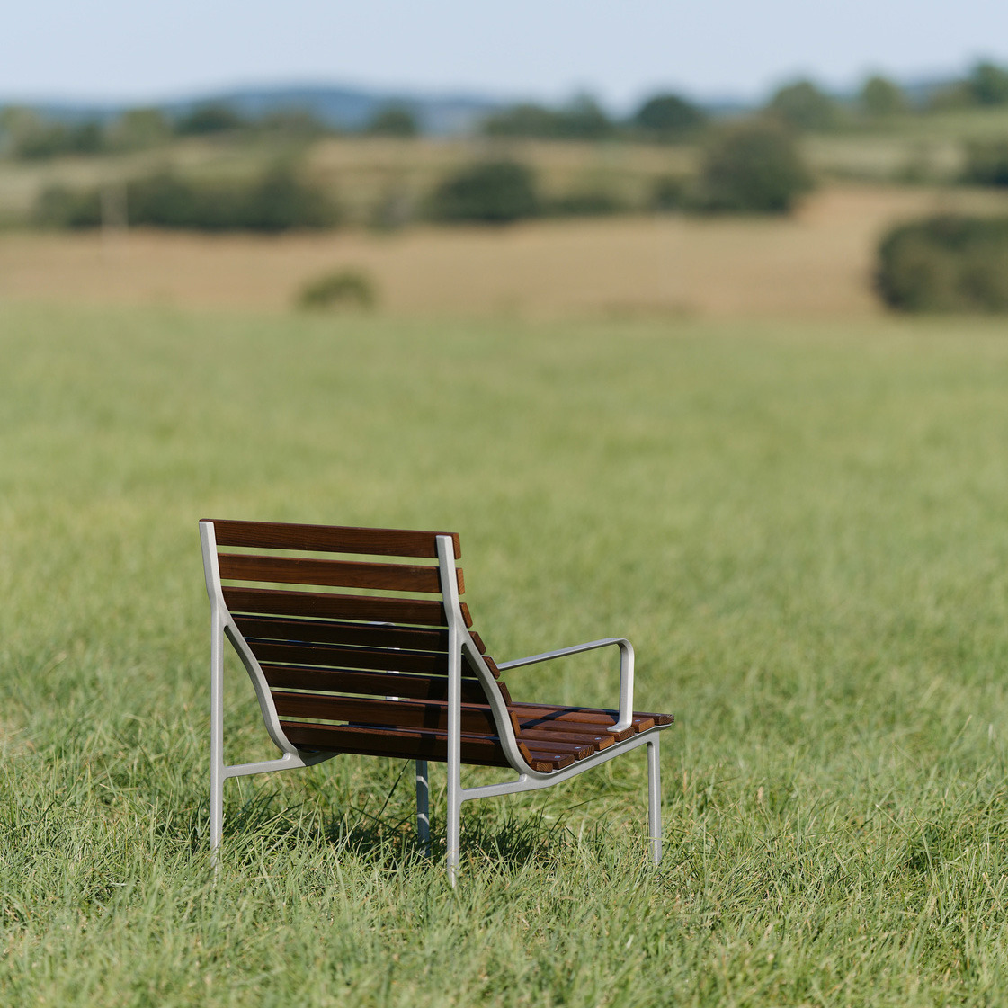 Traverse Armchair with ergonomic design showing natural wood patination and durable aluminum construction