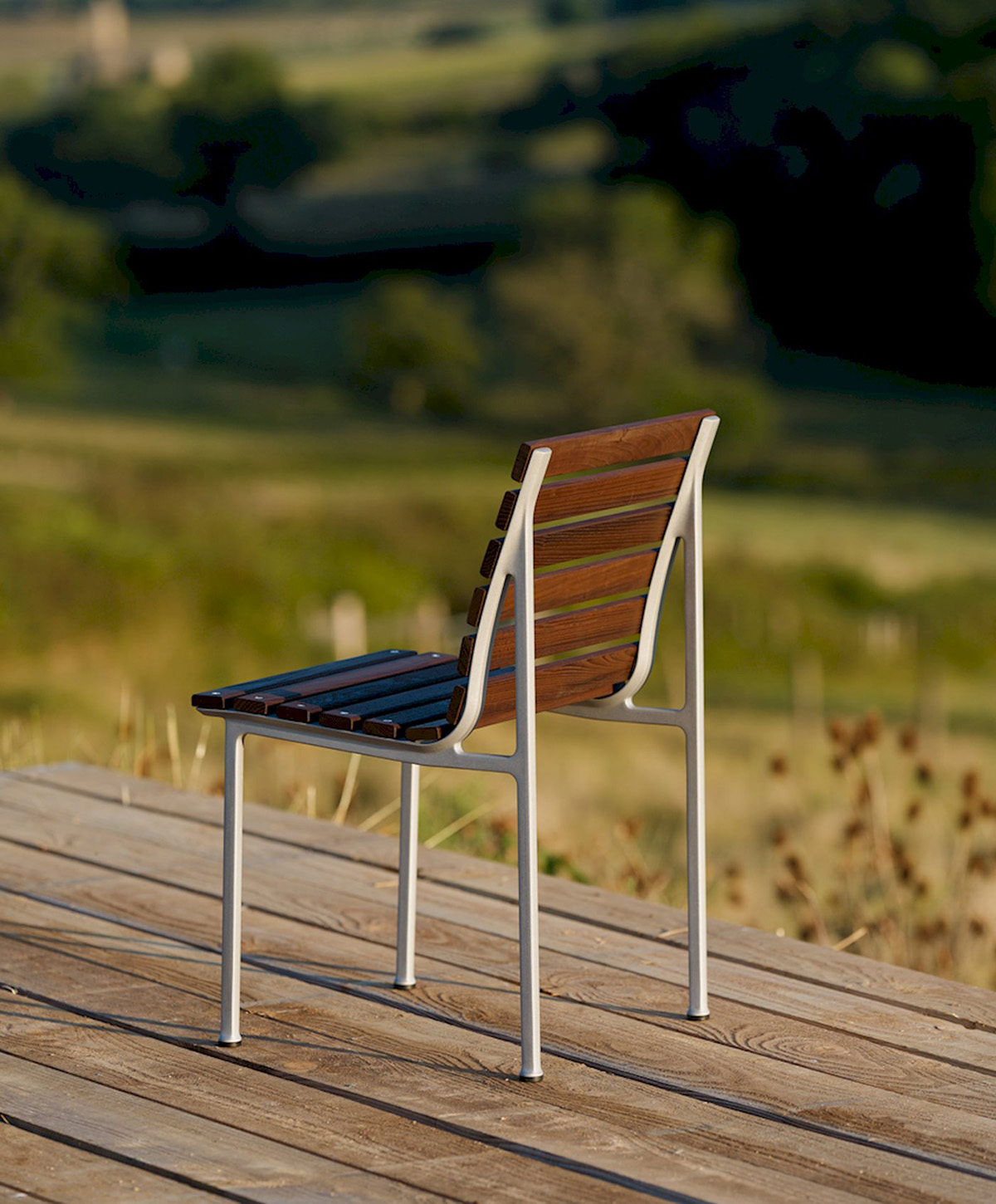 Traverse Chair by Erwan Bouroullec featuring heat-treated ash slats and die-cast aluminum frame in outdoor setting